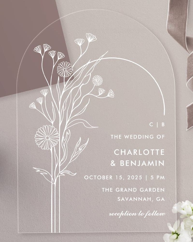 Arch-shaped clear acrylic wedding invitation with a minimalist floral design and wedding details.