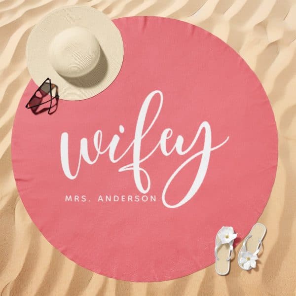 Pink Round Beach Towel With The Word Wifey In White Script Lettering And Mrs. Anderson Below It.