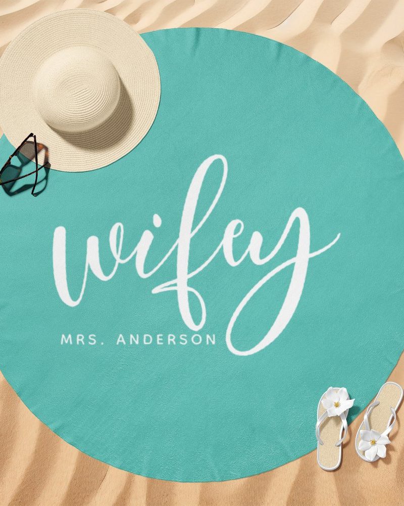 Teal round beach towel with the word wifey and Mrs. Anderson in white script.