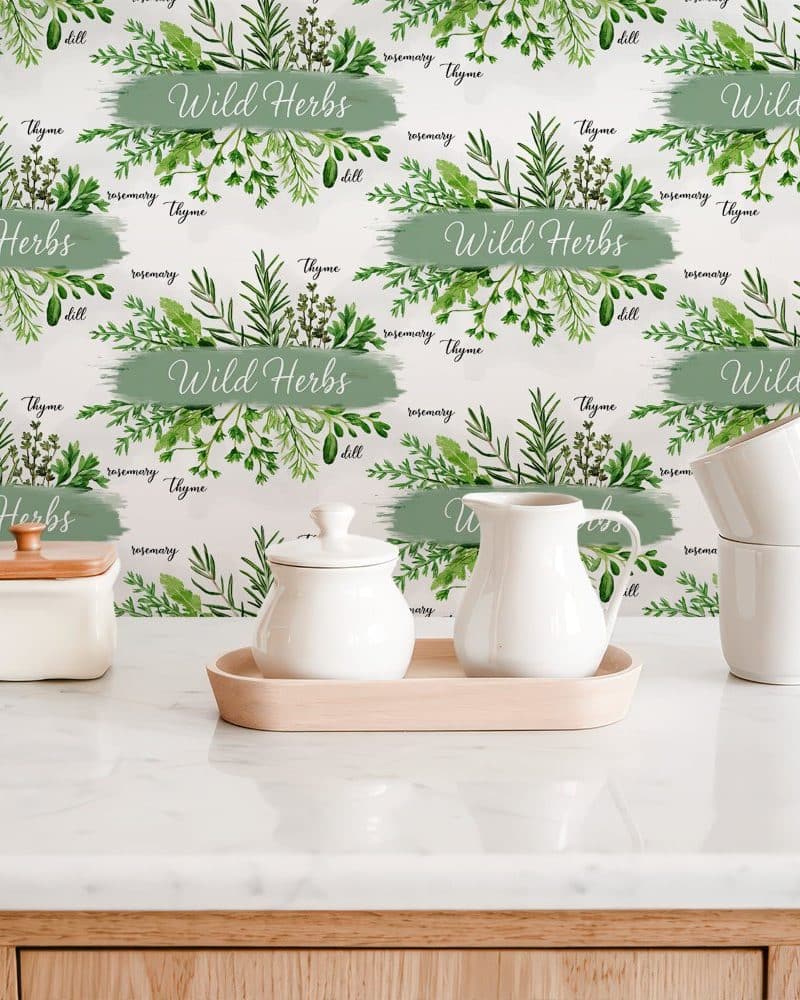 White kitchenware sits on a counter with a backdrop featuring a repeating pattern of watercolor wild herbs and their names.