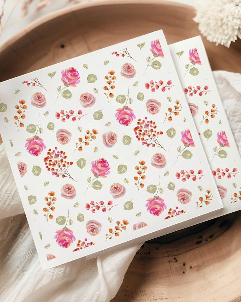 Two square sheets of paper with a watercolor floral pattern featuring pink roses and berries.