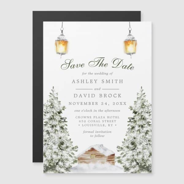 Winter Wedding Save The Date Featuring A Snow-Covered Cabin Between Two Pine Trees, Illuminated By Hanging Lanterns.