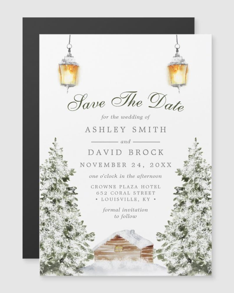 Winter wedding save the date featuring a snow-covered cabin between two pine trees, illuminated by hanging lanterns.
