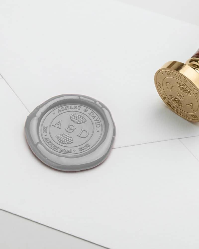 Gray wax seal on a white envelope with the initials A & D, Ashley & David, and wedding date.