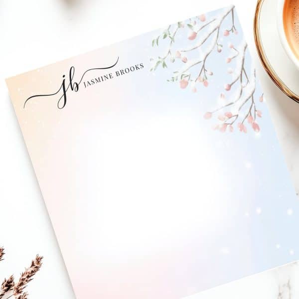Blank Stationery Featuring A Snowy Branch With Pink Blossoms In The Upper Right Corner And A Monogrammed Signature.
