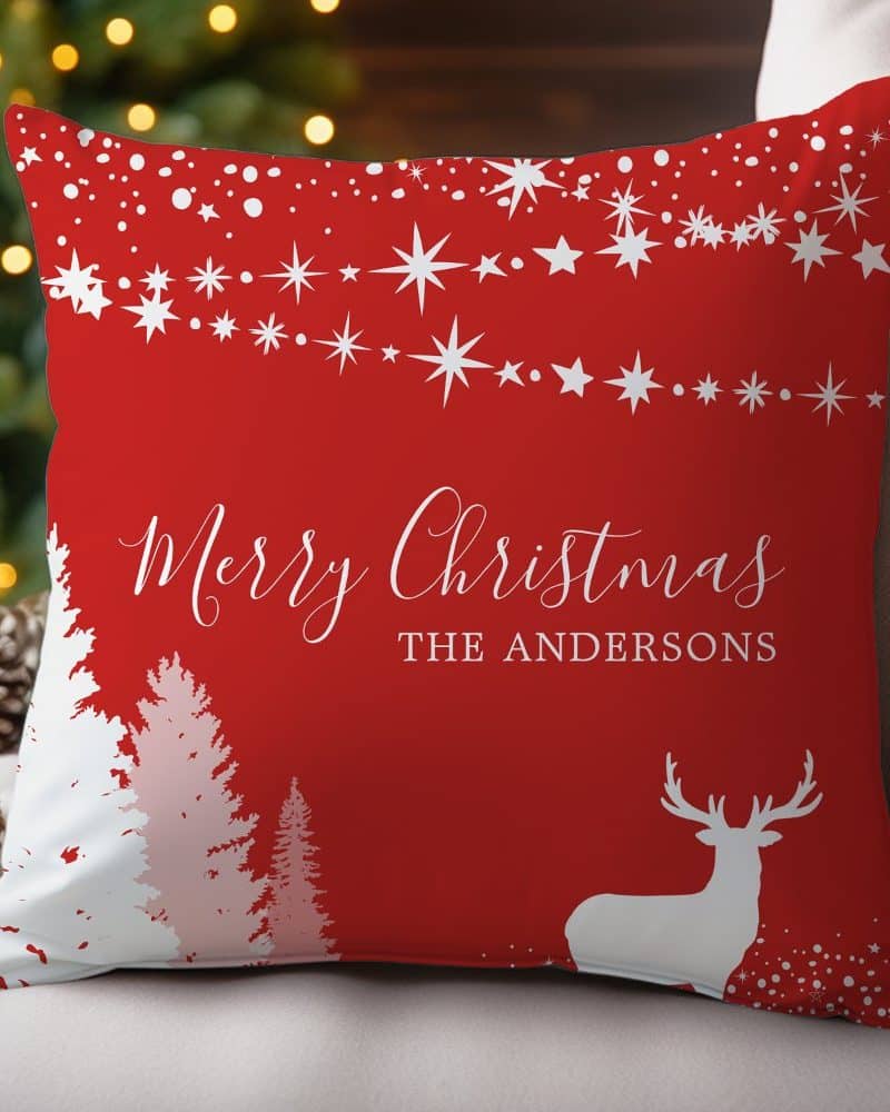 Red Christmas throw pillow with white stars, trees, reindeer, and personalized text.