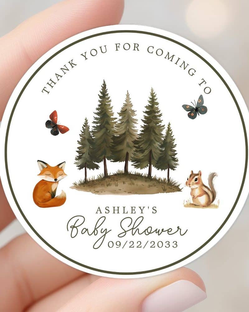 Round baby shower thank you sticker featuring a woodland scene with a fox, chipmunk, trees, and butterflies. Ashleys Baby Shower, 09/22/2033 is written below.