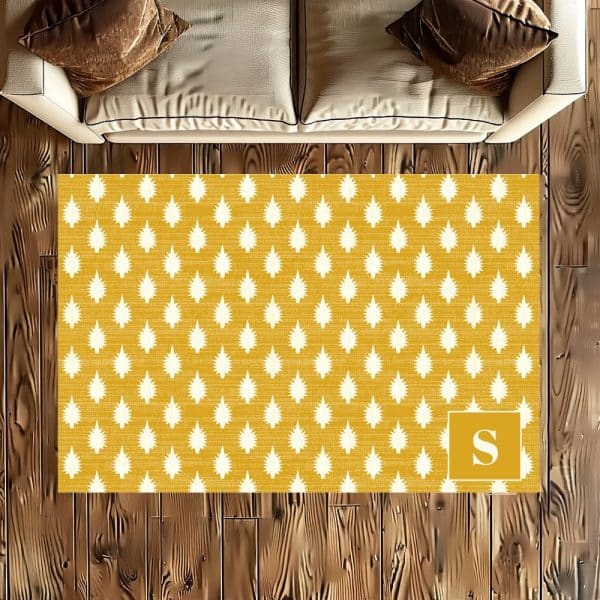 Mustard Yellow Rug With A White Repeating Leaf Pattern And A White Initial S In The Bottom Right Corner.