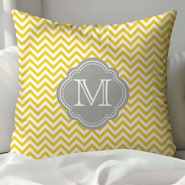 Yellow Chevron Patterned Pillow With A Gray Monogram Of The Letter M.