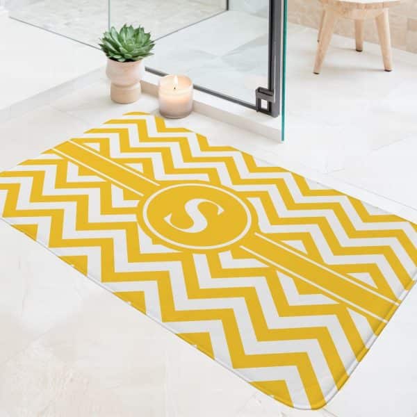 Yellow And White Chevron Bath Mat With A Monogrammed S In A Circle.
