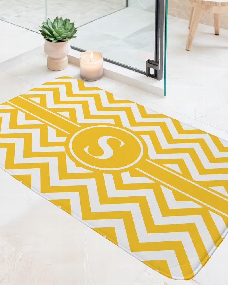 Yellow and white chevron bath mat with a monogrammed S in a circle.