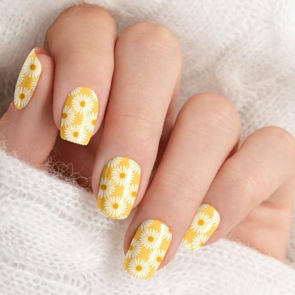 Close Up Of A Hand With Yellow Daisy Nail Polish.