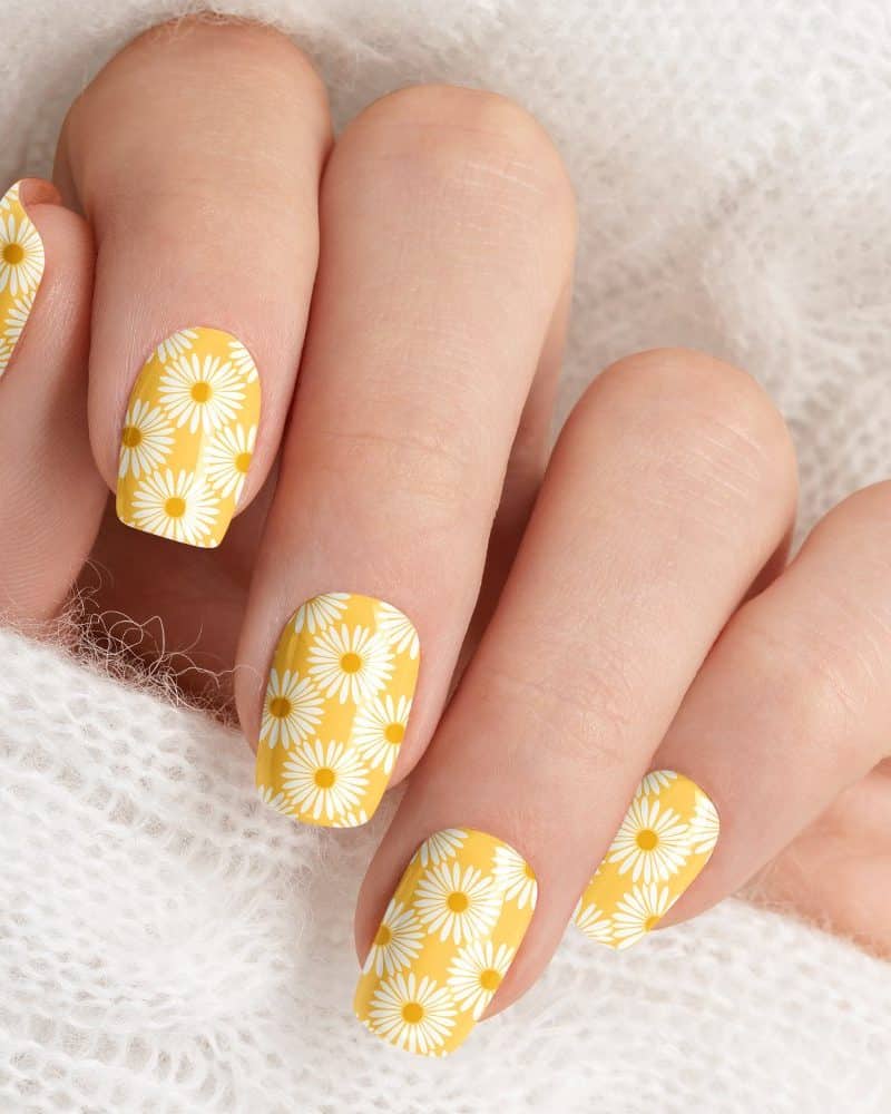 Close up of a hand with yellow daisy nail polish.