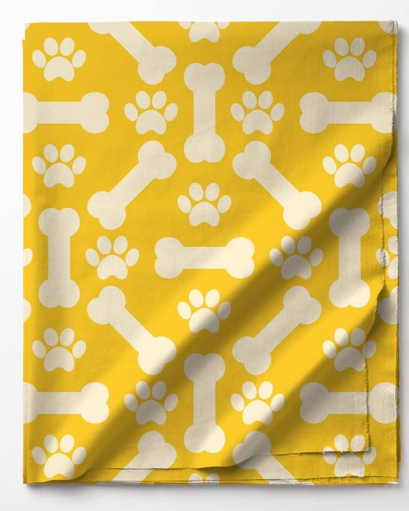 Yellow fabric with a pattern of white bones and paw prints.
