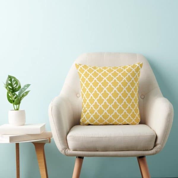 Beige Armchair With A Mustard Yellow Patterned Throw Pillow.