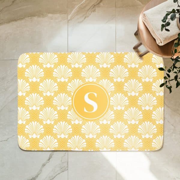 Yellow Bath Mat With A White Seashell Pattern And A Central Yellow Circle Containing The Letter S.