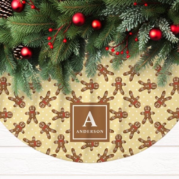 A Christmas Tree Skirt With A Pale Yellow Background Featuring A Repeating Pattern Of Gingerbread Men And White Polka Dots. The Skirt Is Personalized With The Initial A And The Last Name Anderson.
