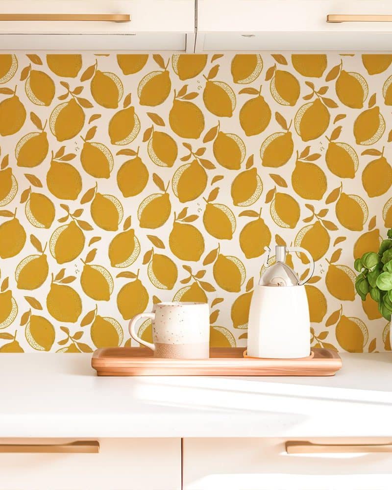 Kitchen counter with a mustard yellow lemon pattern backsplash, a mug, and a creamer.