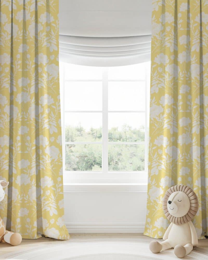 Yellow floral curtains with a white floral pattern hang on a window.