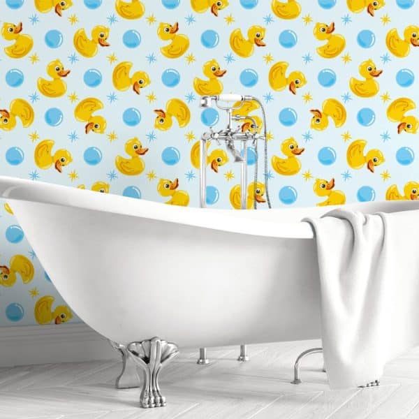White Clawfoot Bathtub In Front Of A Light Blue Wallpaper Featuring Repeating Yellow Rubber Ducks And Blue Bubbles.