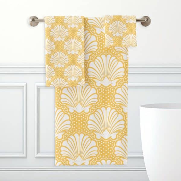 Yellow Bath Towels With A White Seashell Pattern Hanging On A Towel Rack.