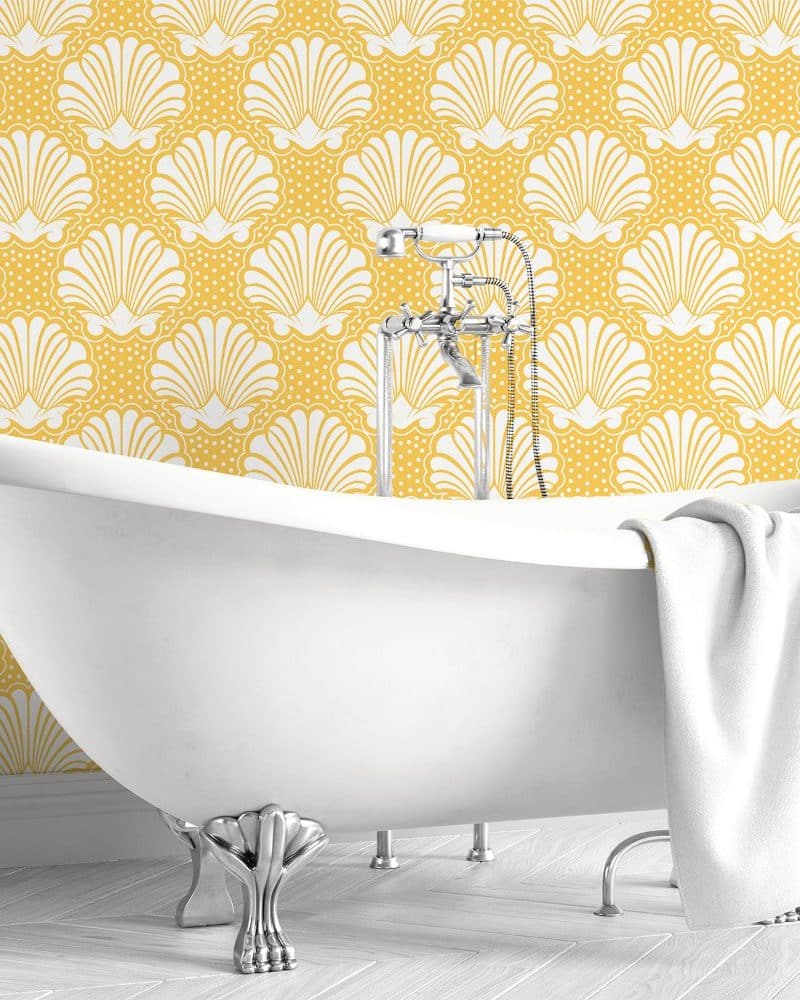 White clawfoot bathtub in front of a yellow seashell patterned wall.