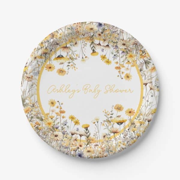 A Round Paper Plate Decorated With A Ring Of Yellow And White Wildflowers, With Ashley'S Baby Shower Written In The Center.