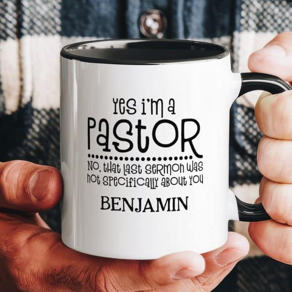 A Hand Holds A White Coffee Mug With Black Text That Says Yes I'M A Pastor, Followed By A Humorous Line About A Sermon, And The Name Benjamin.