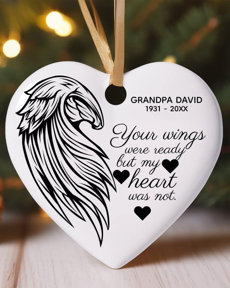 White heart-shaped ornament with a black angel wing design and memorial text.