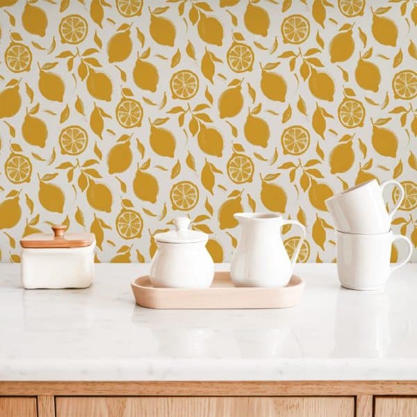 White Kitchenware Sits On A Marble Counter In Front Of A Mustard Yellow Lemon Pattern Wallpaper.