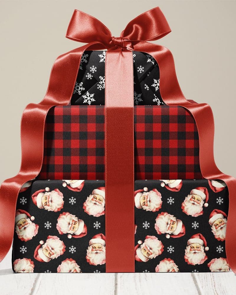 Stack of three Christmas presents tied with a large red ribbon. The wrapping paper features different holiday designs.