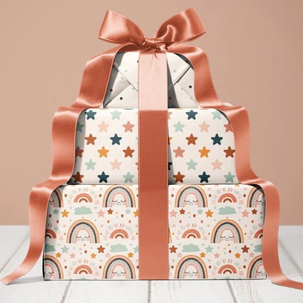 Stack Of Three Gifts Wrapped In Pastel Rainbow And Star Patterned Paper, Tied With A Large Coral Ribbon.