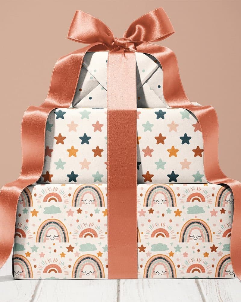 Stack Of Three Gifts Wrapped In Pastel Rainbow And Star Patterned Paper, Tied With A Large Coral Ribbon.