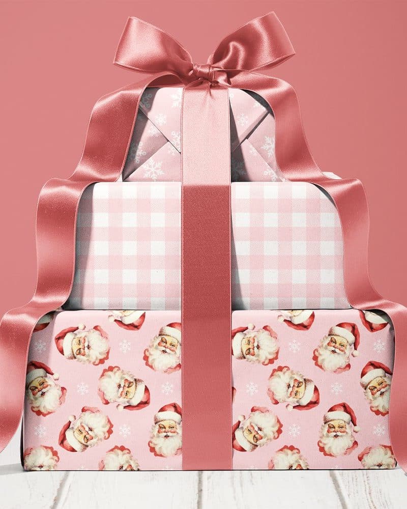Stack of three pink Christmas presents tied with a large rose-gold ribbon.