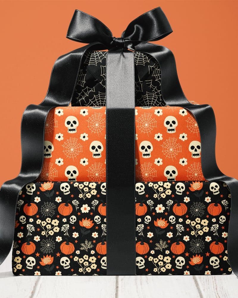Two Halloween-themed gift boxes stacked, tied with a large black ribbon.